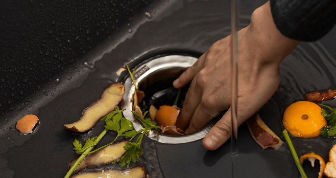 Pessoa acoplando resíduos no triturador Franke